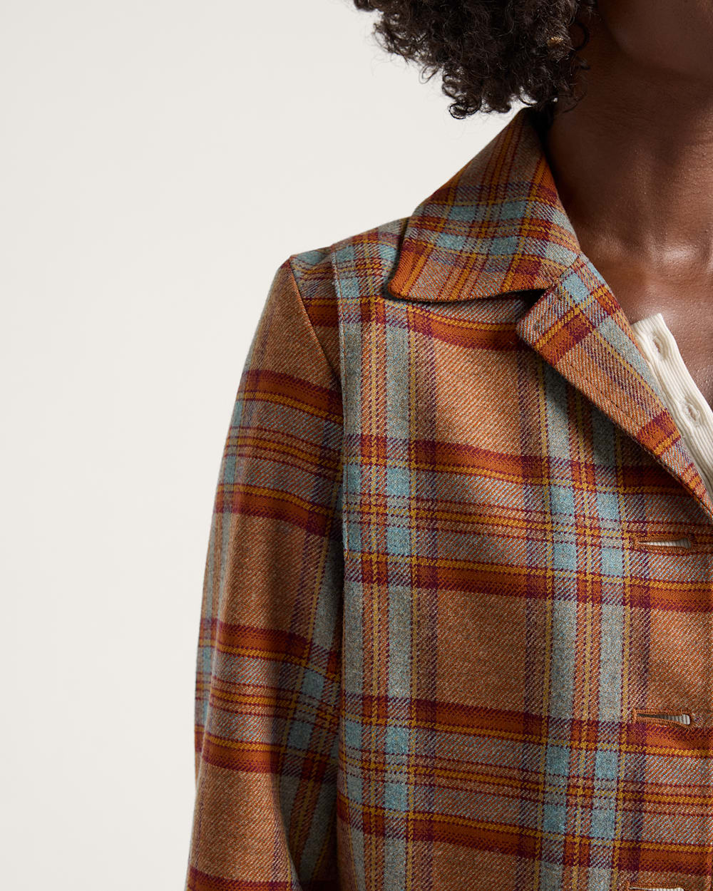 Plaid jacket with a focus on the collar and shoulder area against a neutral background