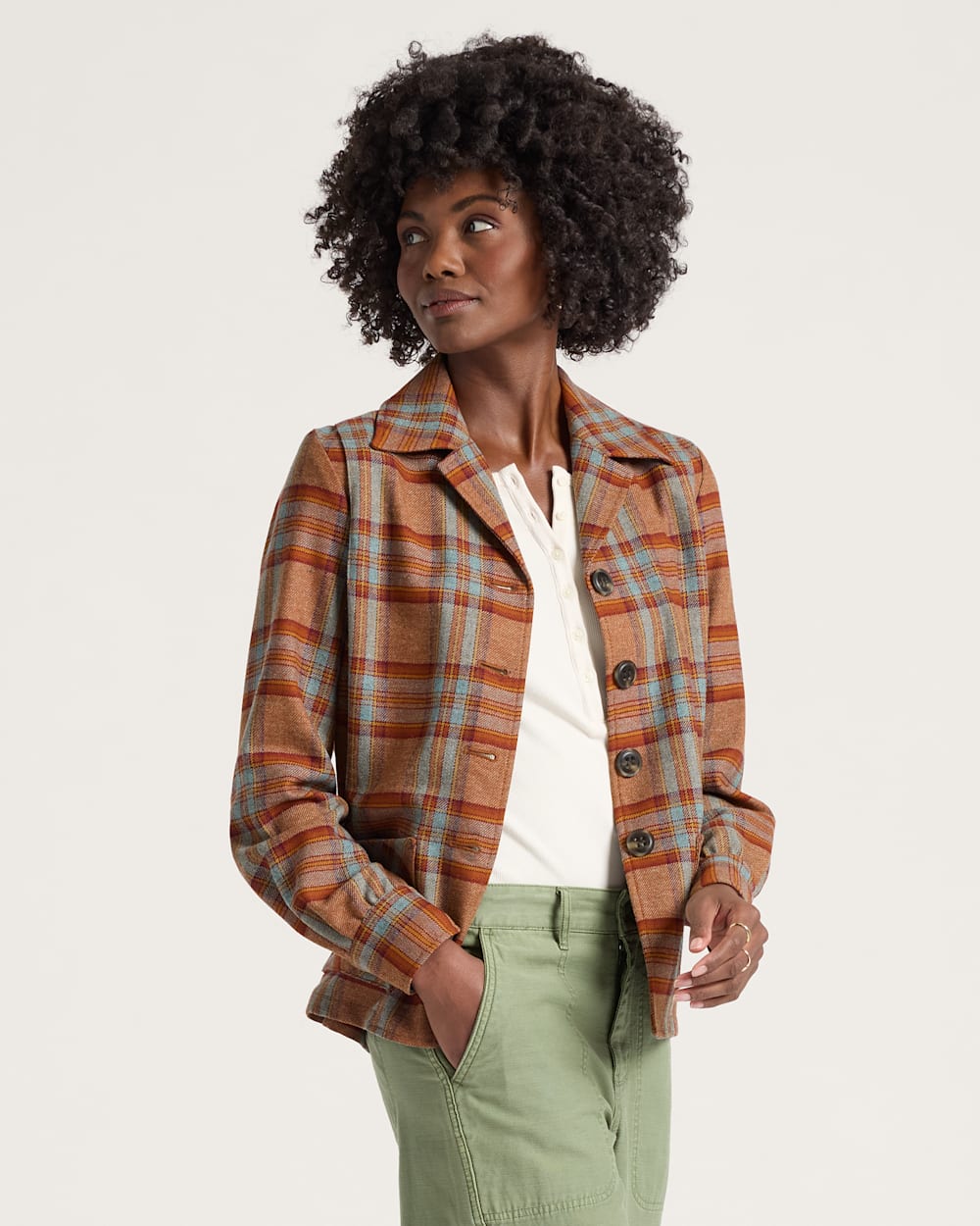 Woman wearing a plaid jacket with a plain background