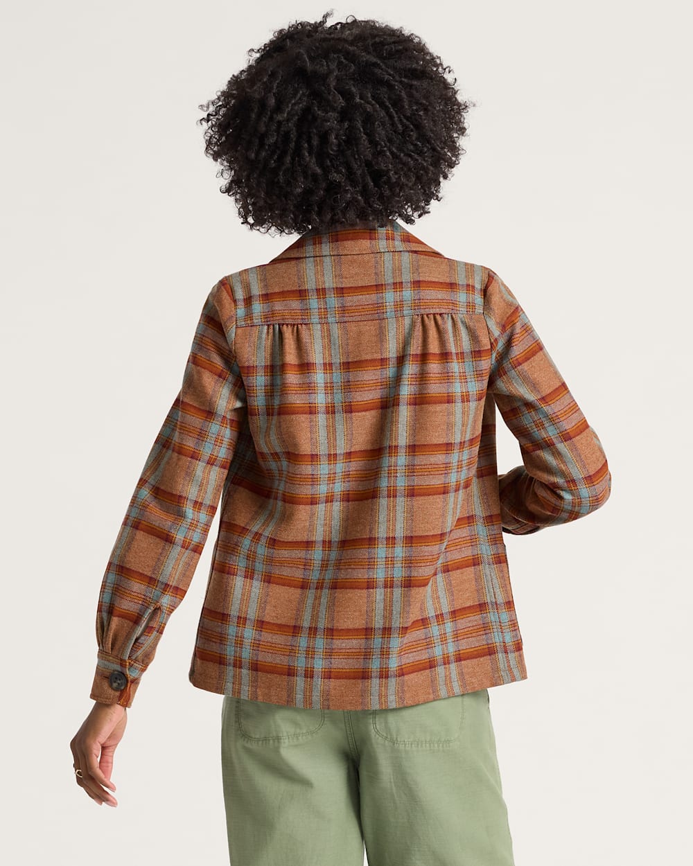 Person wearing a plaid shirt with a neutral background
